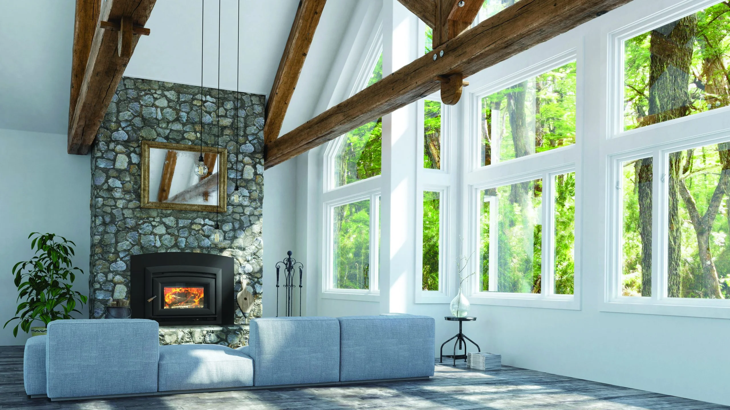 A brightly lit living room with large windows looking out at green trees. The room features a rustic stone wall with a black wood-burning stove insert and visible fire, exposed wooden ceiling beams, a mirror hanging above the fireplace, and a light blue sofa in the foreground.