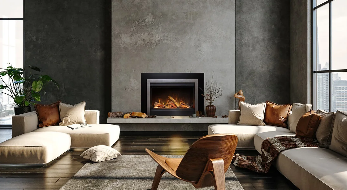 A modern living room with a gray textured wall, a central fireplace, beige sectional sofas with brown and cream pillows, a wooden chair, a gray rug, and large windows overlooking the city.