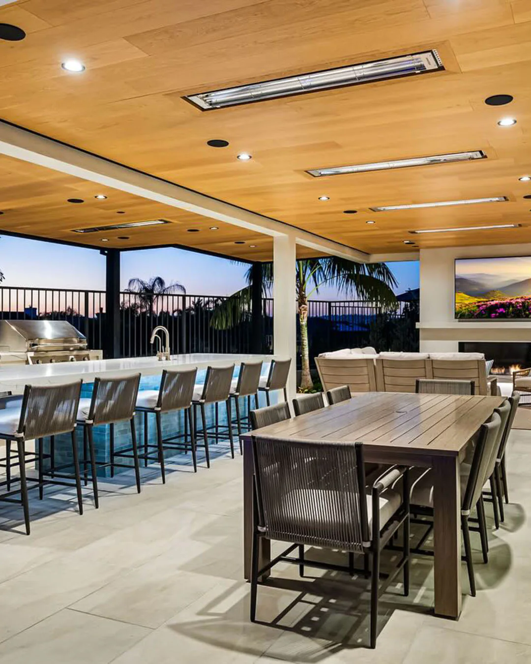 A modern outdoor patio at night with a large built-in fireplace as the focal point. People seated on