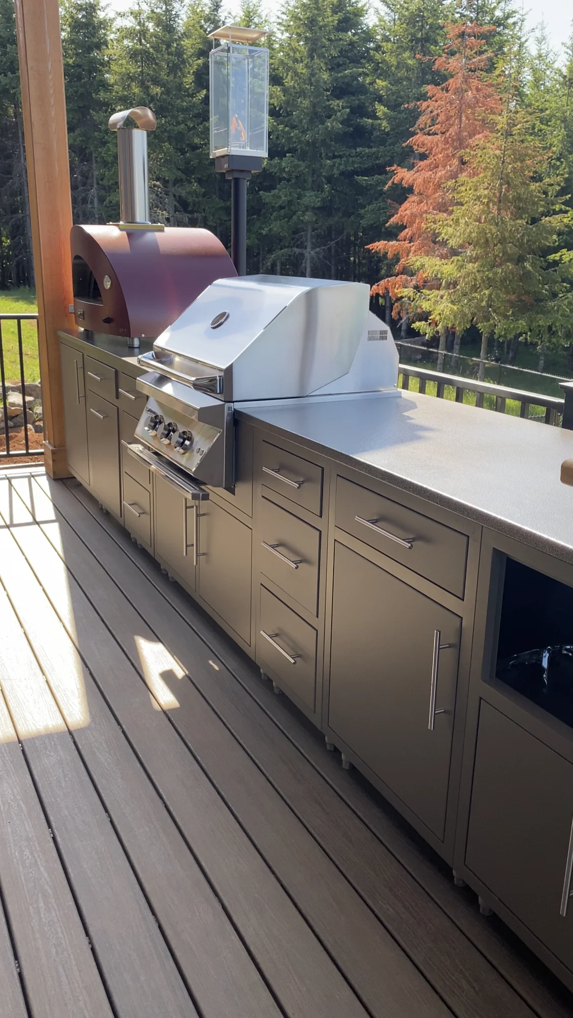 Modern outdoor grill overlooking colorful trees.