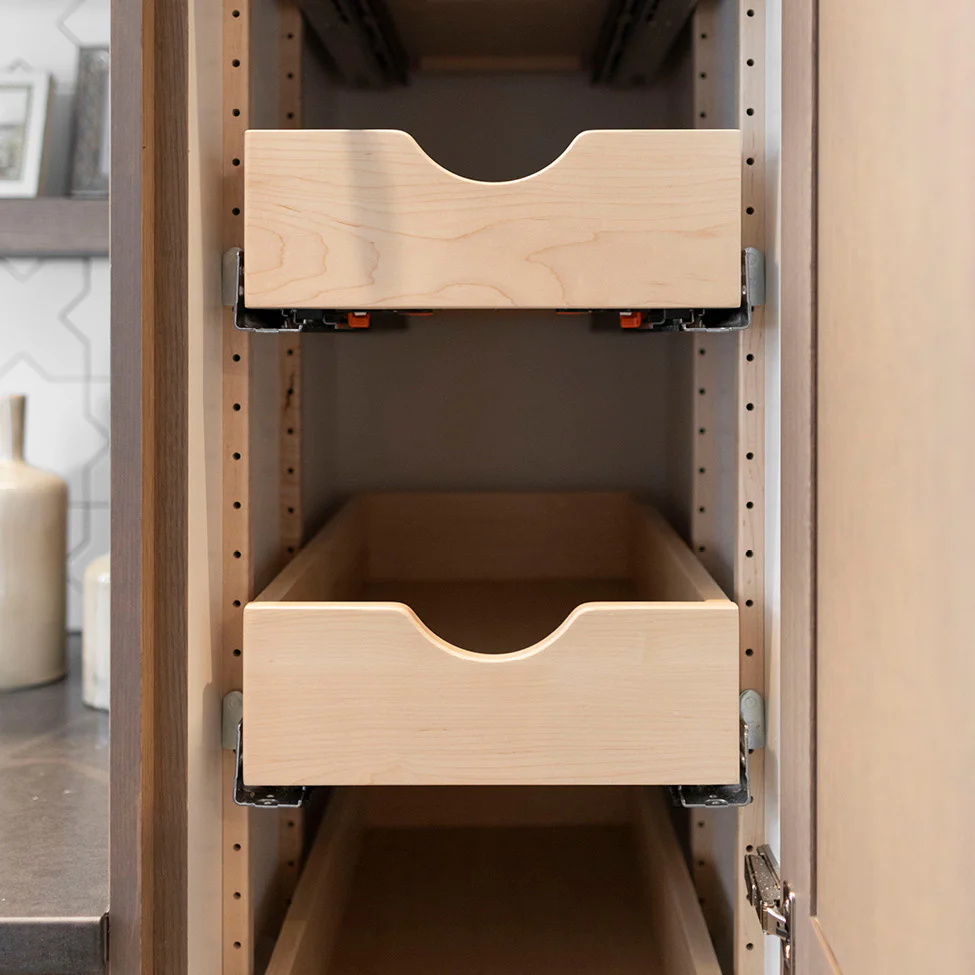 Interior view of a kitchen cabinet with two light wood pull-out drawers on metal slides