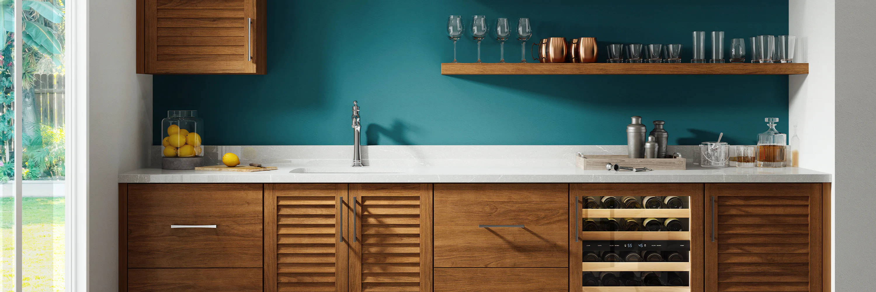 Modern kitchen with teal backsplash, wooden cabinets, and white countertops. Features include a sink, wine cooler, open shelving with glassware, and a bowl of lemons by a large window.