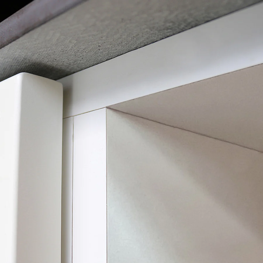 Close-up of a white cabinet corner with clean lines under a gray, textured countertop edge, showing precise alignment and modern design.