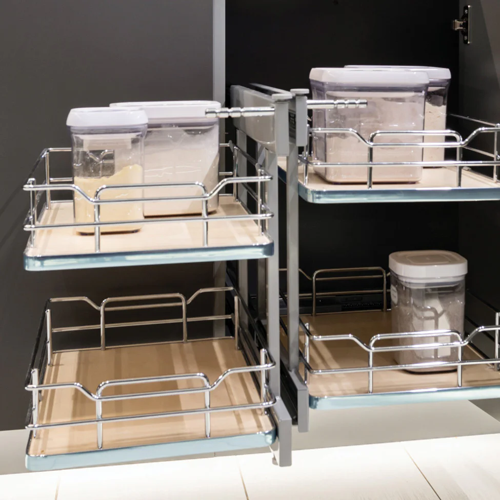 Pull-out kitchen cabinet with chrome-framed sliding shelves holding clear plastic food containers of flour and sugar