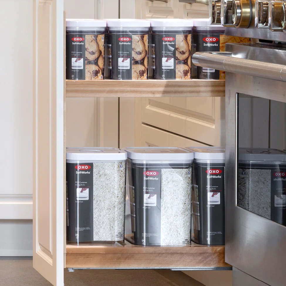 Pull-out kitchen cabinet shelf holding OXO SoftWorks airtight food storage containers with rice and cookies