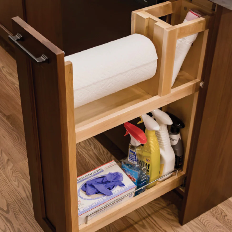 Pull-out wooden cabinet shelf with paper towel roll, spray cleaners, and a box of disposable gloves