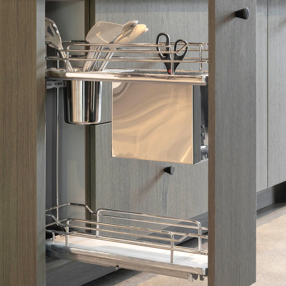 Pull-out kitchen cabinet organizer with metal utensil rack holding spatulas, scissors, and a small bin