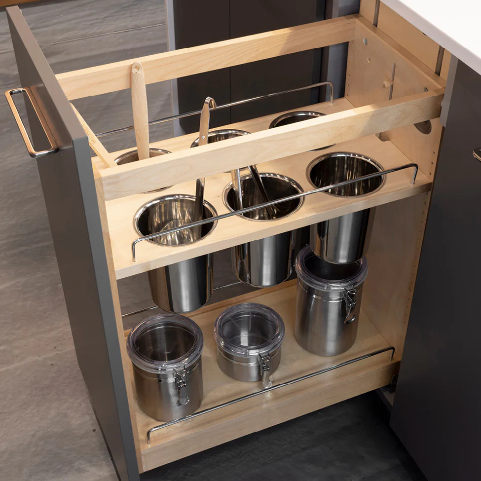 Pull-out kitchen cabinet organizer with wooden frame holding stainless steel canisters and lidded jars on two shelves