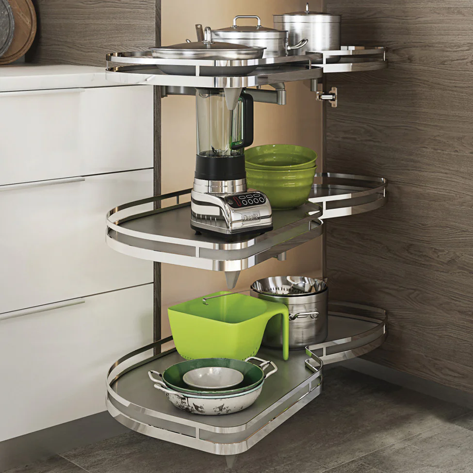 Stainless steel corner pull-out kitchen shelves holding a blender, green bowls and assorted pots and pans