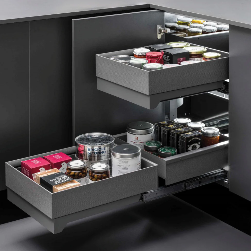 Corner kitchen cabinet with three pull-out gray drawers holding jars, cans and packaged pantry items