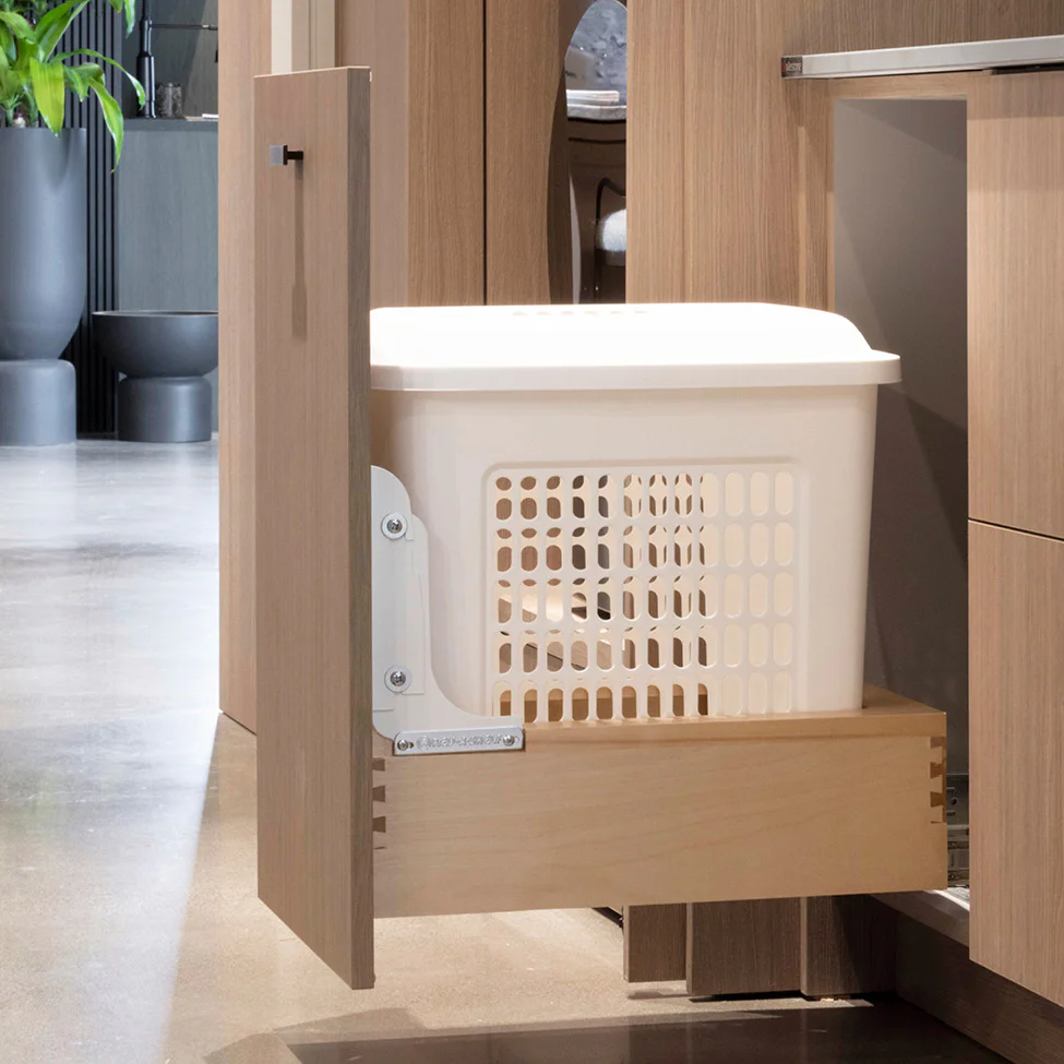 Pull-out cabinet drawer holding a white plastic storage basket in a modern kitchen