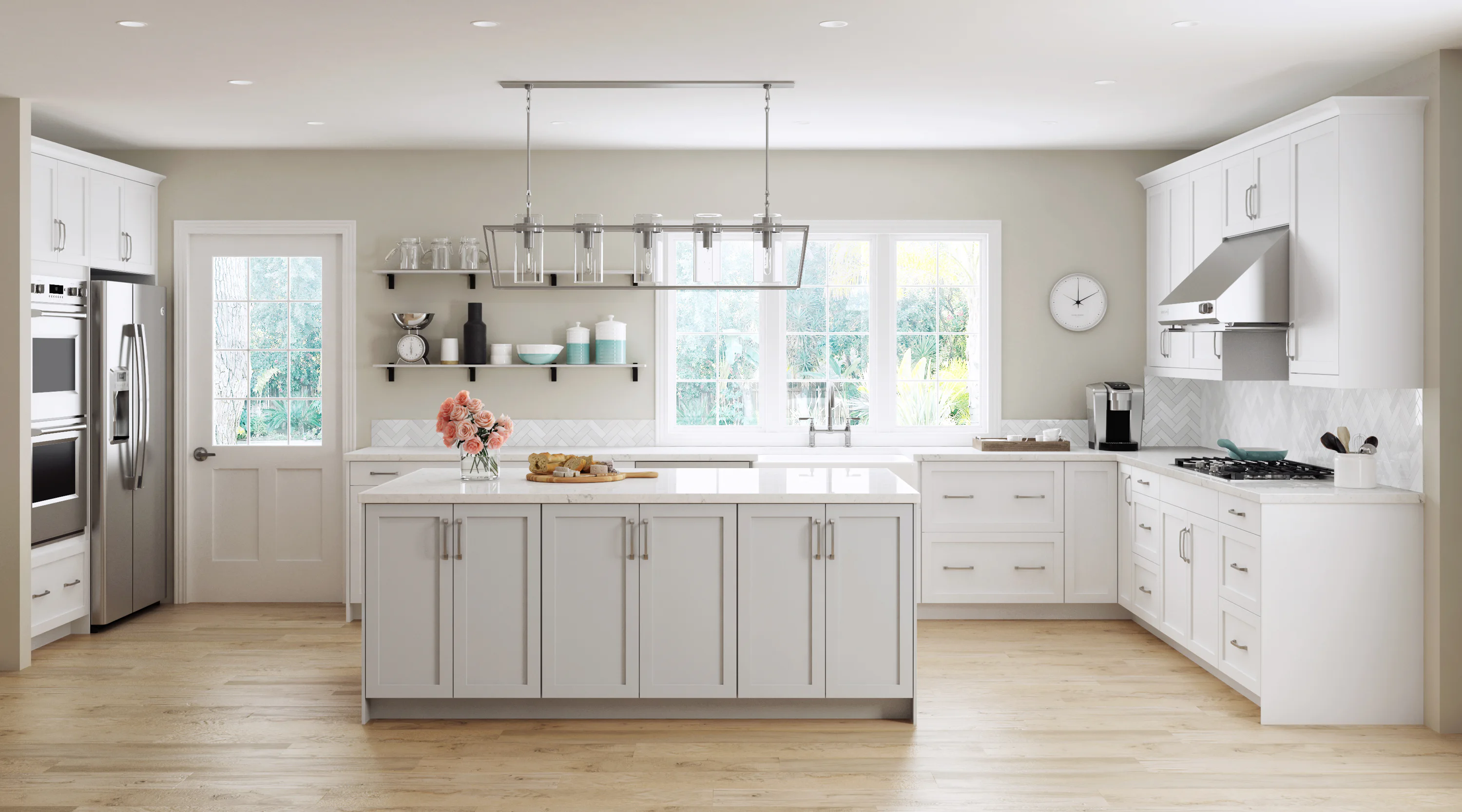 Modern kitchen with white cabinetry, central island with flowers, stainless steel appliances, a hanging light fixture, and large windows overlooking greenery. Light wood flooring.