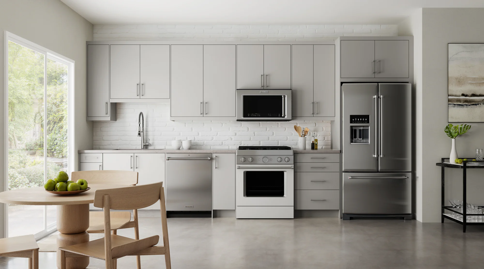 Bright modern kitchen with gray cabinets, stainless steel appliances, white brick backsplash, table with green apples