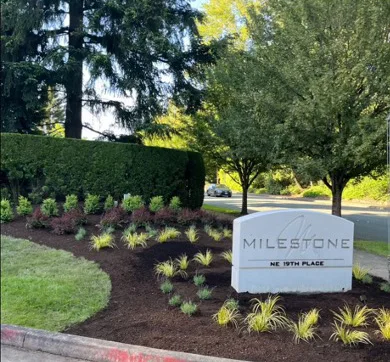 A landscaped area with a white sign reading 