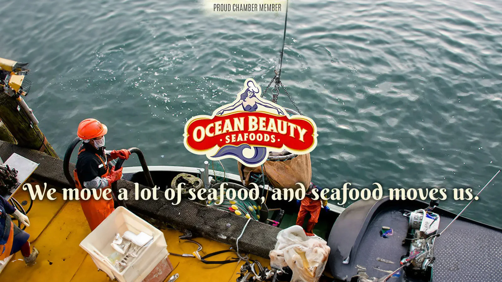 Fishing boat on the water with workers in orange gear. The Ocean Beauty Seafoods logo is visible with the text, 