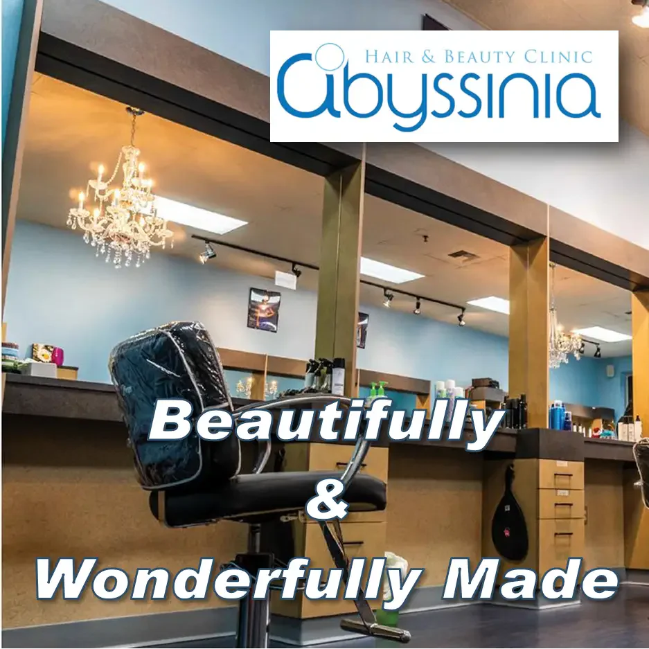 Hair salon interior with a chandelier, salon chair, and mirrored stations. 