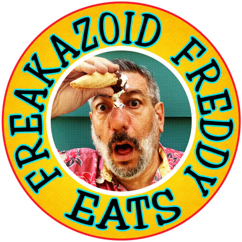 Man with a shocked expression holds a melting ice cream cone to his forehead. He wears a floral shirt, and the text around him reads Freakazoid Freddy Eats.