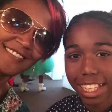 A woman in sunglasses and a child posing for a selfie
