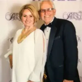 A couple in formal wear posing on a red carpet