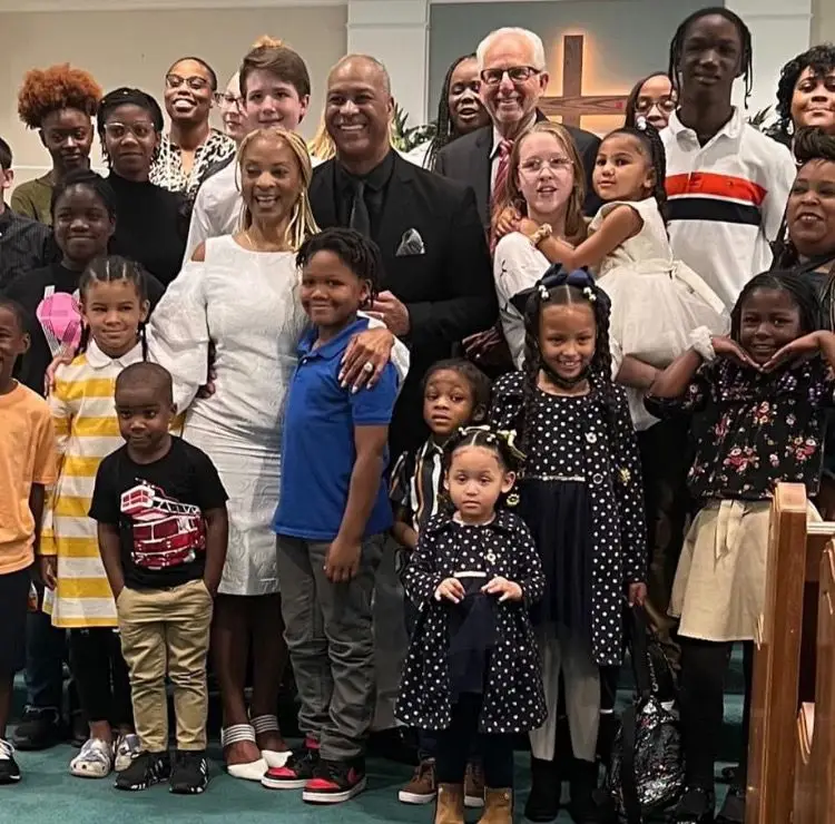 Adults and children of the Covenant Life Cathedral family smiling together inside the church, a large cross behind them